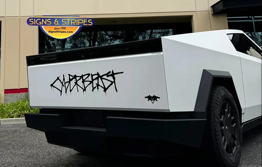 White Cybertruck wrap with black Cyberbeast decals on the tailgate